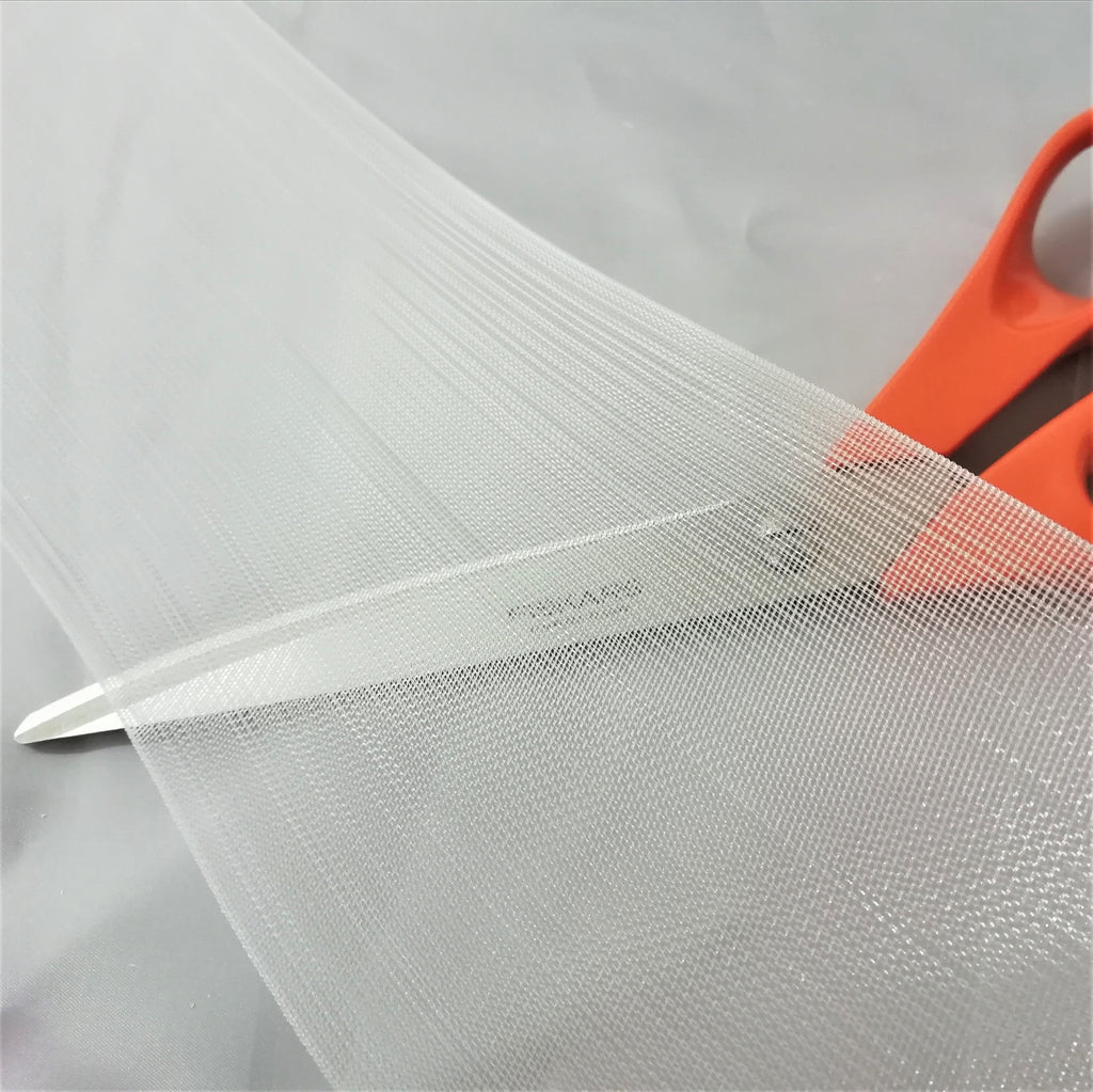 A close up of translucent buckram with a pair of scissors underneath to show the translucent properties